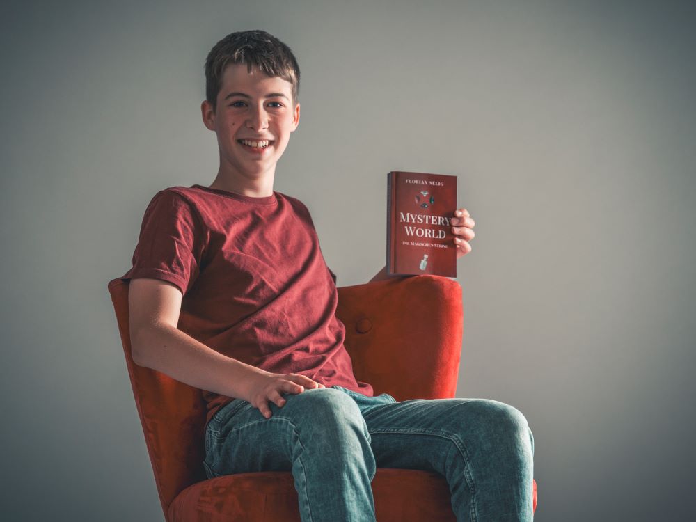 Flori Sessel Buch 2 Der junge Autor Florian Selig hält sein Buch "Mystery World, die magischen Steine",